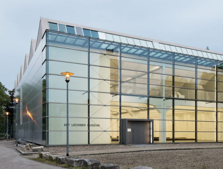 Außenansicht des Alf‑Lechner‑Museums in Neumarkt: Kubischer Bau mit silbrig‑grauer, leicht gewellter Metallfassade und flachem Satteldach